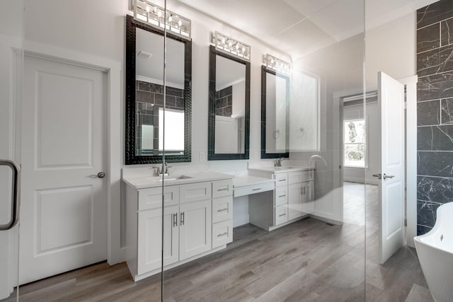 bathroom with tile walls, hardwood / wood-style floors, a bath, and vanity