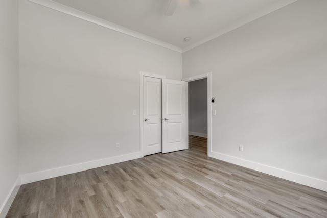 empty room with light wood-type flooring, ceiling fan, a high ceiling, and crown molding