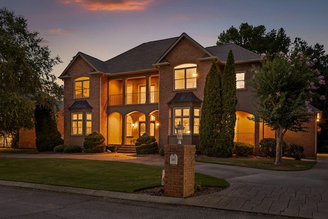 view of front of home with a balcony and a yard