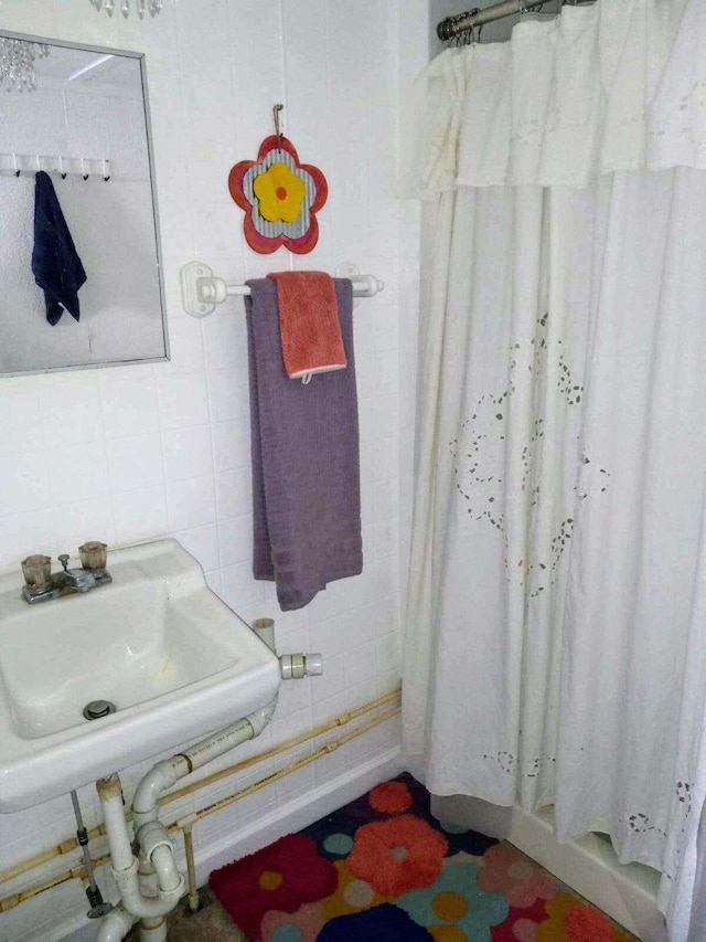 bathroom with tile walls, sink, and curtained shower