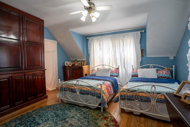 bedroom featuring light hardwood / wood-style flooring, vaulted ceiling, and ceiling fan