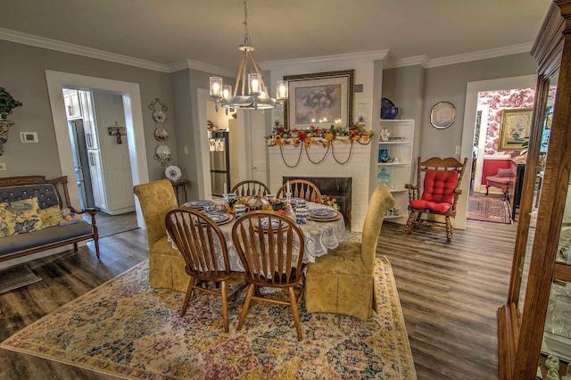 dining room with ornamental molding, a fireplace, an inviting chandelier, and dark hardwood / wood-style flooring