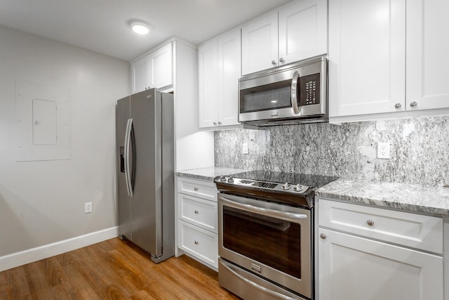 kitchen featuring stainless steel appliances, light stone countertops, white cabinetry, and tasteful backsplash