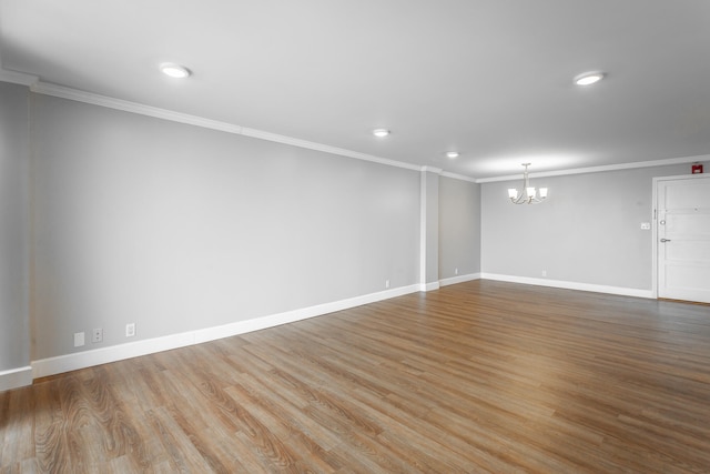 spare room featuring baseboards, ornamental molding, wood finished floors, a chandelier, and recessed lighting