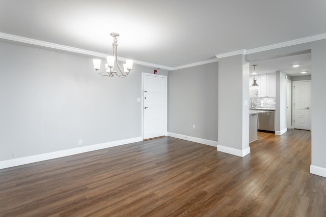 empty room featuring dark wood-type flooring, ornamental molding, baseboards, and an inviting chandelier