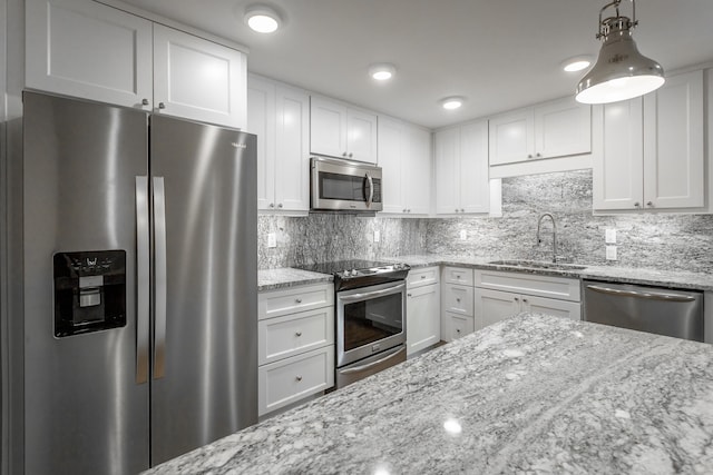 kitchen with white cabinets, pendant lighting, sink, tasteful backsplash, and appliances with stainless steel finishes