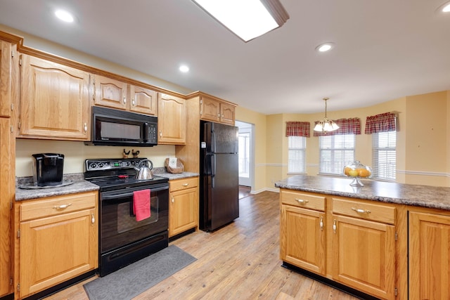 kitchen featuring an inviting chandelier, light hardwood / wood-style flooring, hanging light fixtures, and black appliances