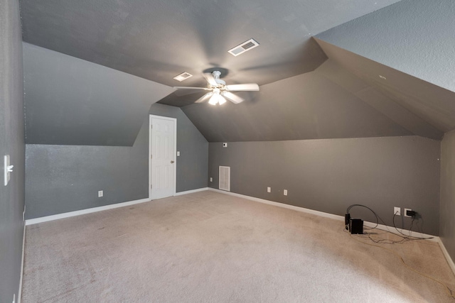 additional living space with a textured ceiling, carpet, vaulted ceiling, and ceiling fan