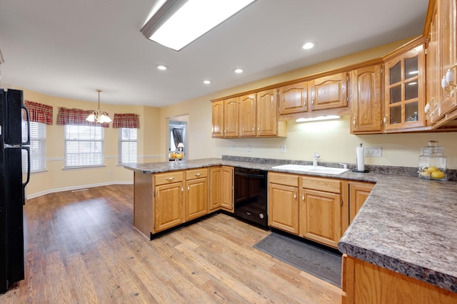 kitchen featuring light wood-type flooring, a notable chandelier, kitchen peninsula, hanging light fixtures, and black appliances