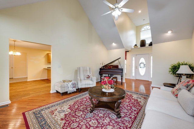 living room featuring ceiling fan with notable chandelier, hardwood / wood-style floors, and high vaulted ceiling