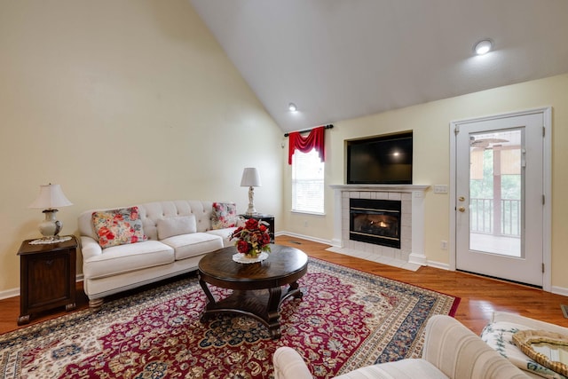 living room featuring a fireplace, light hardwood / wood-style flooring, and high vaulted ceiling