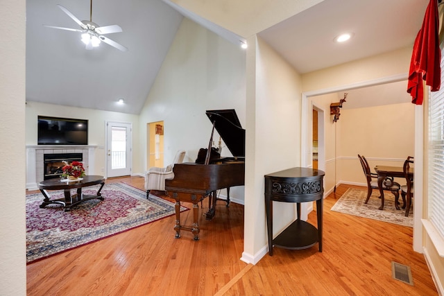 interior space featuring ceiling fan, hardwood / wood-style flooring, a fireplace, and high vaulted ceiling