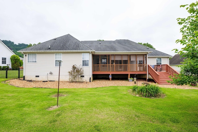 rear view of property with a wooden deck, a lawn, and a sunroom