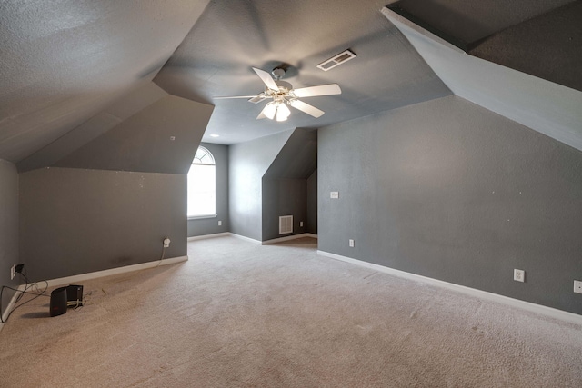 additional living space featuring ceiling fan, a textured ceiling, light carpet, and vaulted ceiling