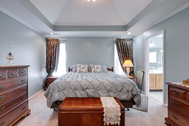 bedroom featuring light carpet, a raised ceiling, and connected bathroom