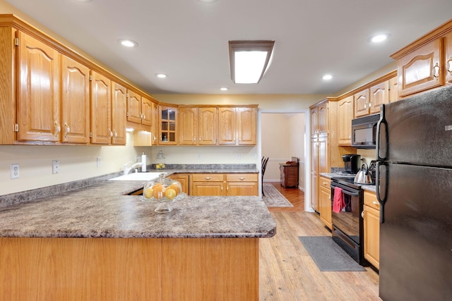 kitchen with sink, light hardwood / wood-style flooring, kitchen peninsula, and black appliances