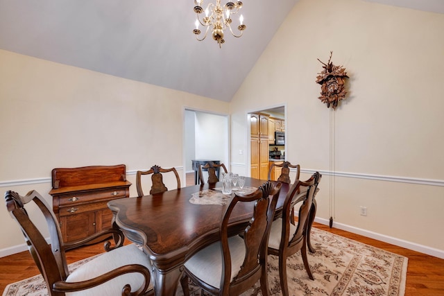 dining room with a notable chandelier, high vaulted ceiling, and hardwood / wood-style flooring