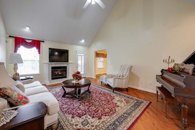 living room with ceiling fan, a fireplace, light hardwood / wood-style floors, and high vaulted ceiling