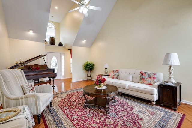 living room with ceiling fan, light hardwood / wood-style floors, and high vaulted ceiling