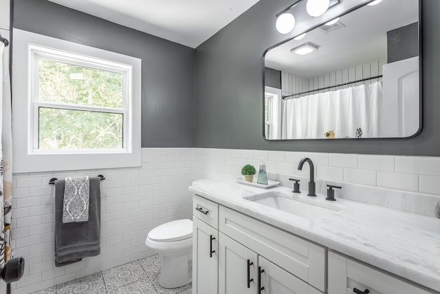 bathroom featuring toilet, tile walls, a shower with curtain, vanity, and tile patterned flooring