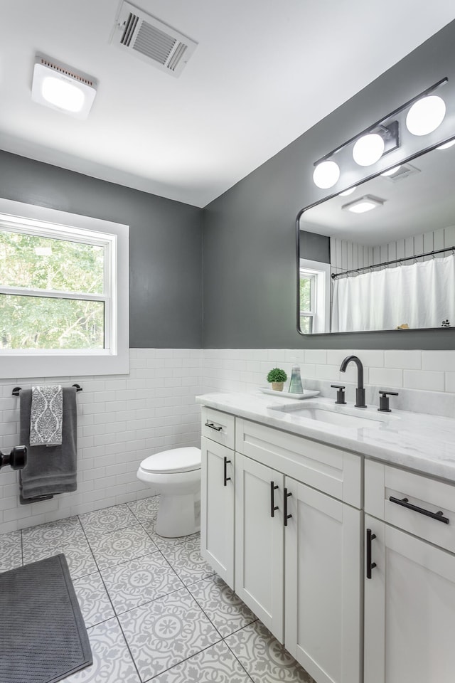 bathroom featuring tile walls, vanity, toilet, and tile patterned floors