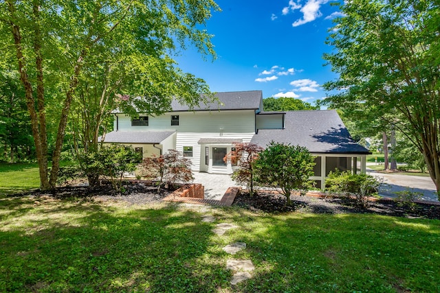 rear view of house featuring a yard and a sunroom