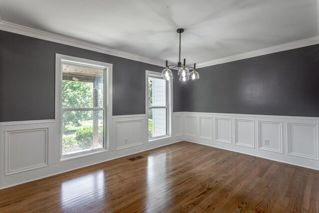 unfurnished dining area with crown molding, dark hardwood / wood-style flooring, and an inviting chandelier