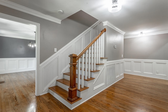 stairs featuring ornamental molding, hardwood / wood-style flooring, and a chandelier