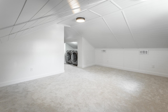 additional living space with washing machine and dryer, vaulted ceiling, and light colored carpet