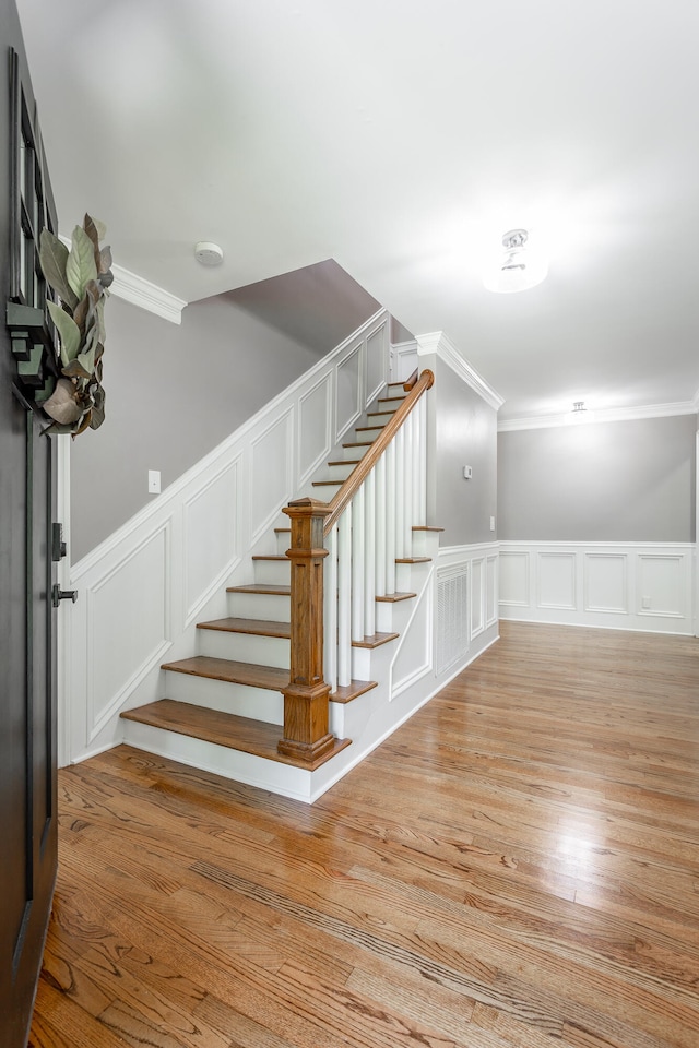 staircase featuring crown molding and wood-type flooring