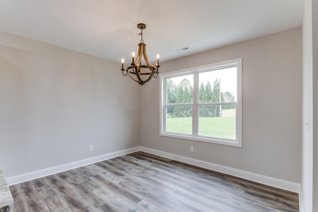 unfurnished room featuring wood-type flooring and an inviting chandelier