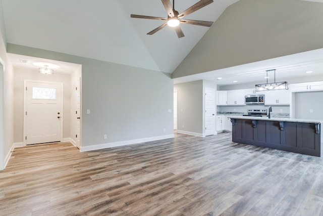 unfurnished living room featuring ceiling fan, sink, high vaulted ceiling, and light hardwood / wood-style floors