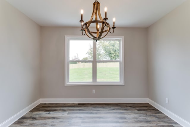 empty room featuring dark hardwood / wood-style flooring and an inviting chandelier