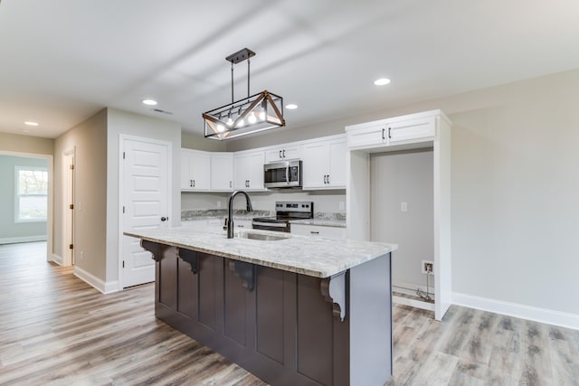 kitchen with white cabinets, sink, stainless steel appliances, and a kitchen island with sink