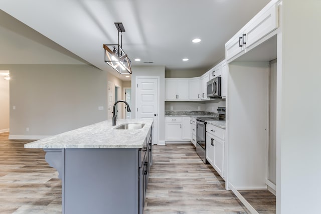 kitchen with stainless steel appliances, sink, a center island with sink, light hardwood / wood-style floors, and white cabinetry