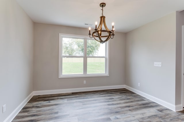 spare room featuring dark wood-type flooring and a chandelier