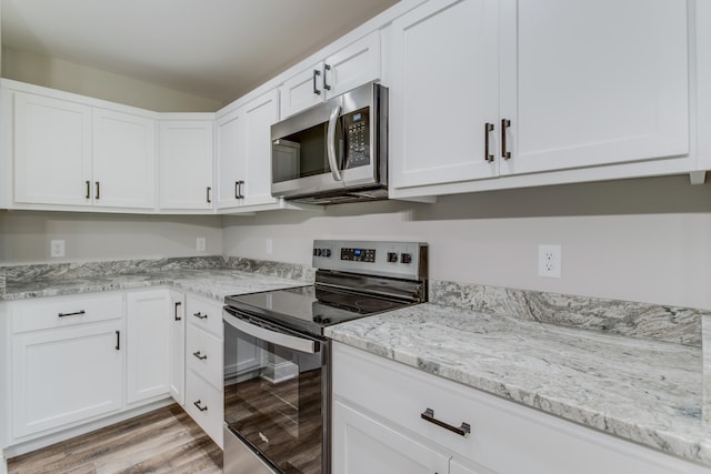 kitchen featuring white cabinetry, light hardwood / wood-style flooring, light stone countertops, and appliances with stainless steel finishes