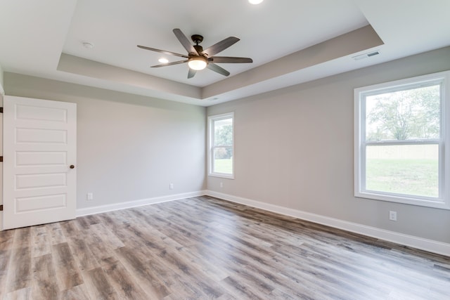 spare room with a raised ceiling, ceiling fan, and light hardwood / wood-style floors