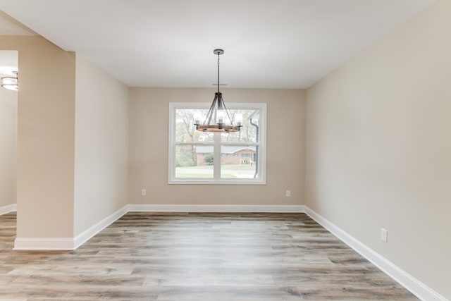 spare room featuring light hardwood / wood-style flooring and a notable chandelier