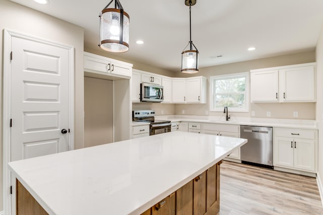 kitchen with white cabinets, a center island, hanging light fixtures, and appliances with stainless steel finishes