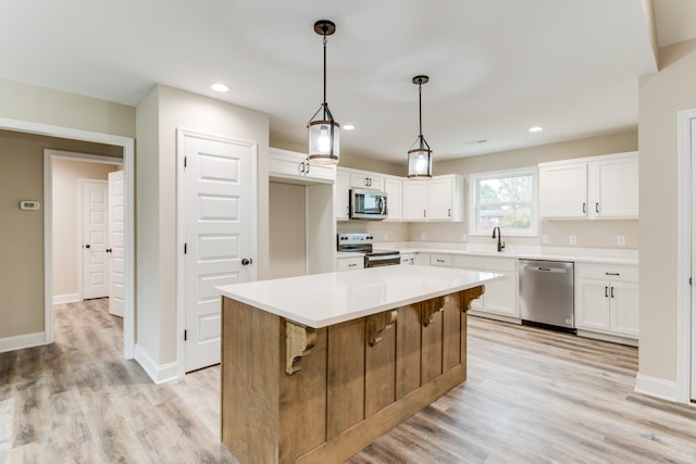 kitchen featuring a center island, white cabinets, stainless steel appliances, and light hardwood / wood-style floors