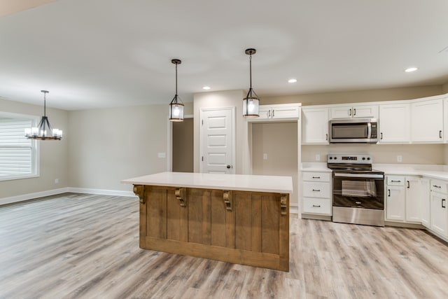 kitchen with stainless steel appliances, a kitchen island, light hardwood / wood-style flooring, pendant lighting, and white cabinets