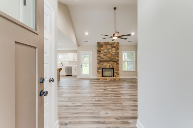 unfurnished living room featuring ceiling fan, a fireplace, high vaulted ceiling, and light wood-type flooring