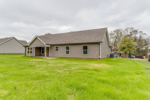 rear view of property with a yard and central air condition unit