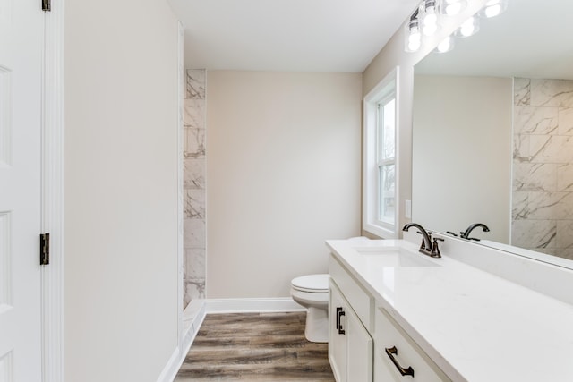 bathroom featuring tiled shower, hardwood / wood-style floors, vanity, and toilet