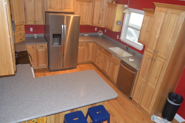 kitchen featuring sink, hanging light fixtures, light hardwood / wood-style flooring, appliances with stainless steel finishes, and light brown cabinetry