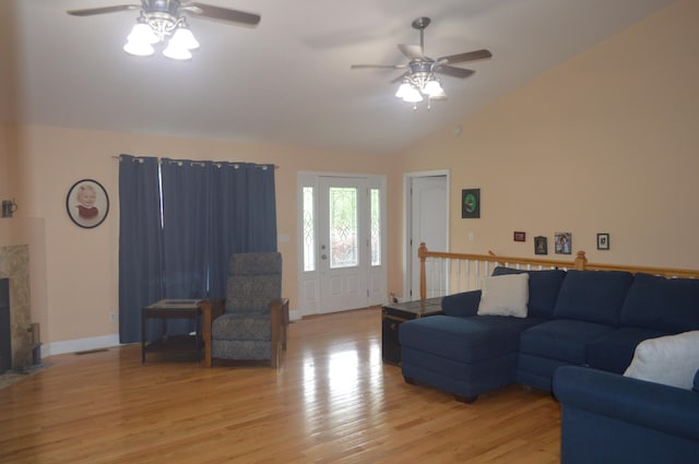 living room with a fireplace, vaulted ceiling, ceiling fan, and light hardwood / wood-style flooring