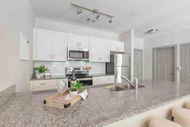 kitchen featuring a breakfast bar, stainless steel appliances, white cabinets, and sink