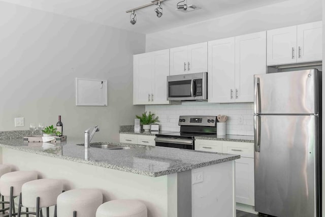 kitchen featuring light stone counters, white cabinets, a breakfast bar area, and appliances with stainless steel finishes