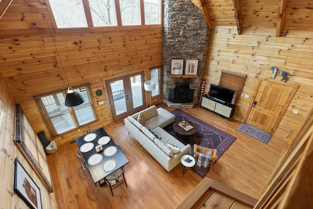 living room featuring wood-type flooring, wood walls, beam ceiling, and high vaulted ceiling